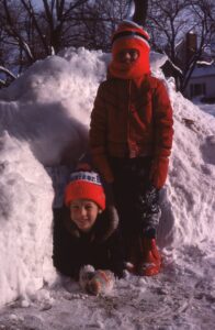 Karl and Adam standing next to a four foot tall pile of snow during the blizzard of 1977.